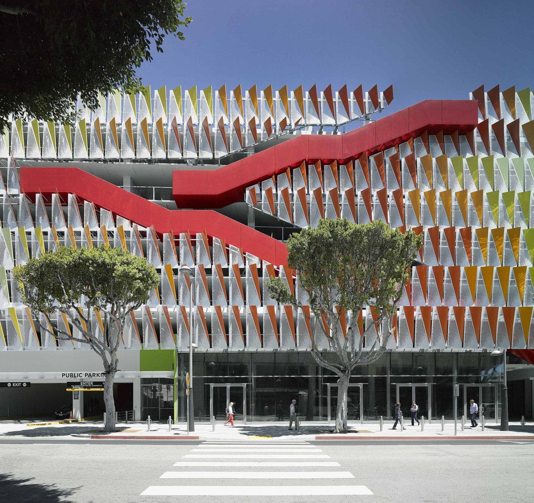 Completed City of Santa Monica 4th Street Parking Structure, with a perforated metal facade in orange, green, and yellow panels and a red diagonal stair volume